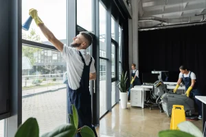 Professional cleaners inside an office building wiping the windows and mopping the floor