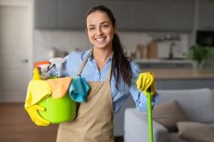 Professional cleaner from Diamond Touch Cleaners smiling at the camera while holding a bucket of cleaning equipment and a mop