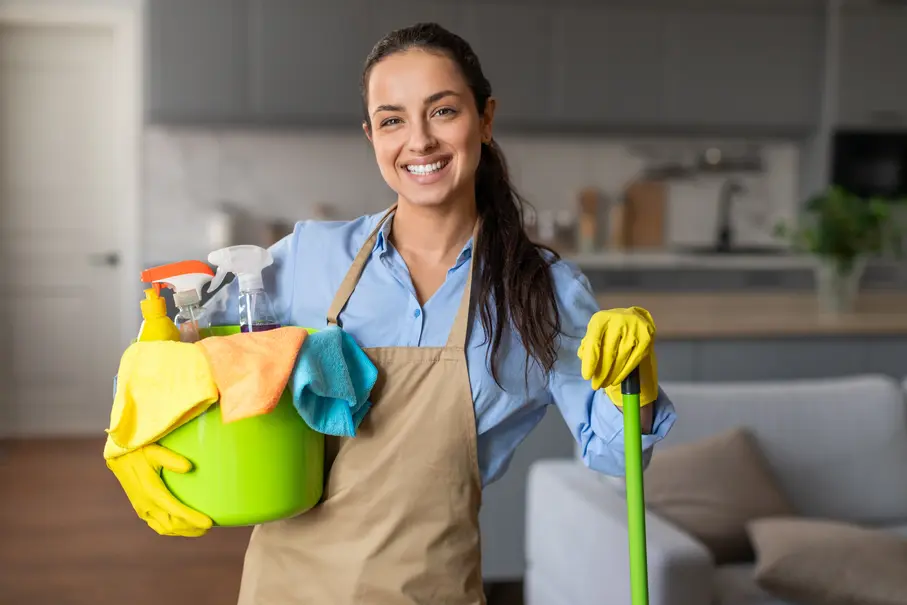 Professional cleaner from Diamond Touch Cleaners smiling at the camera while holding a bucket of cleaning equipment and a mop