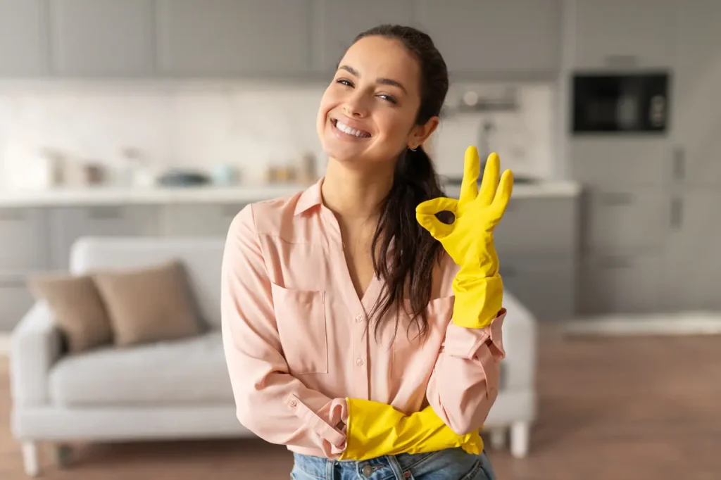 Professional cleaning woman smiling while looking at the camera making a hand gesture