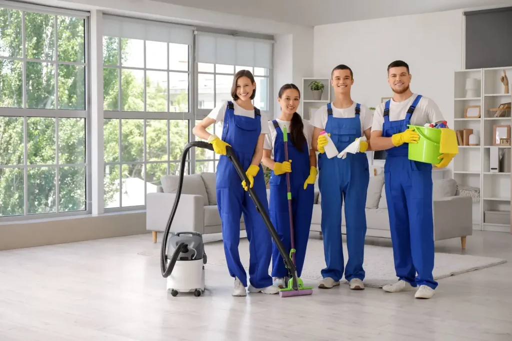 Four professional cleaners in a residential home holding various pieces of cleaning equipment
